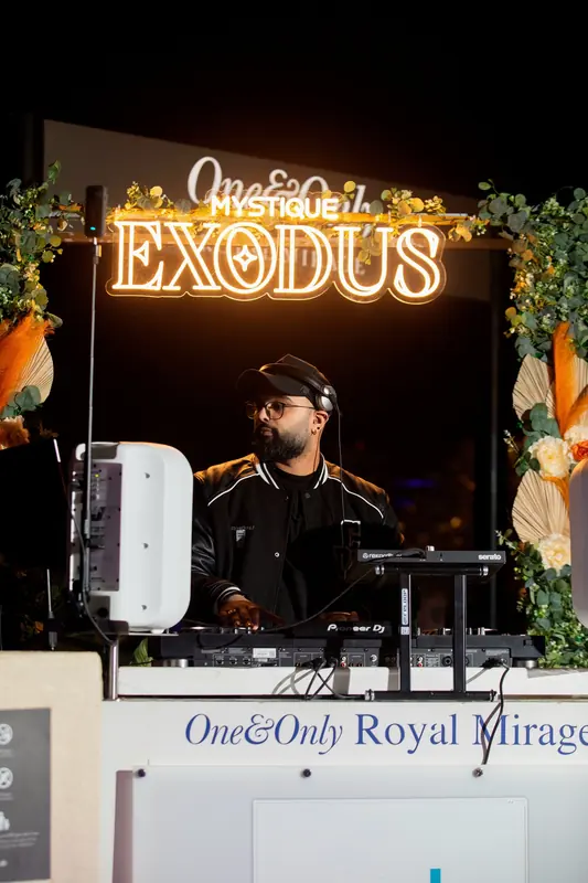 Just AMN DJing in the booth beneath the illuminated Mystique Exodus sign at One&Only Royal Mirage, Dubai